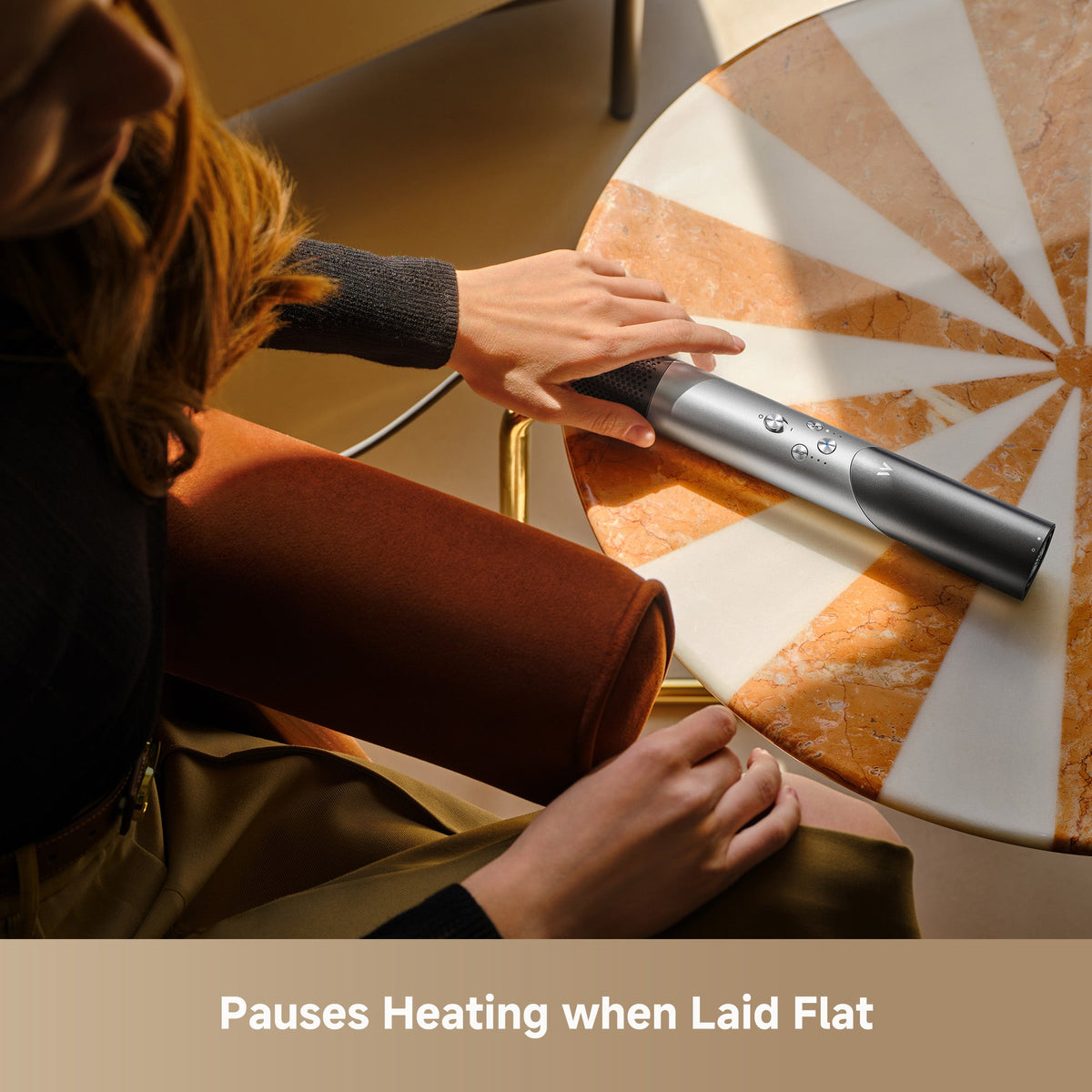 Hands laying the MOVA Master 10 styler flat on a table, where its heating pauses automatically