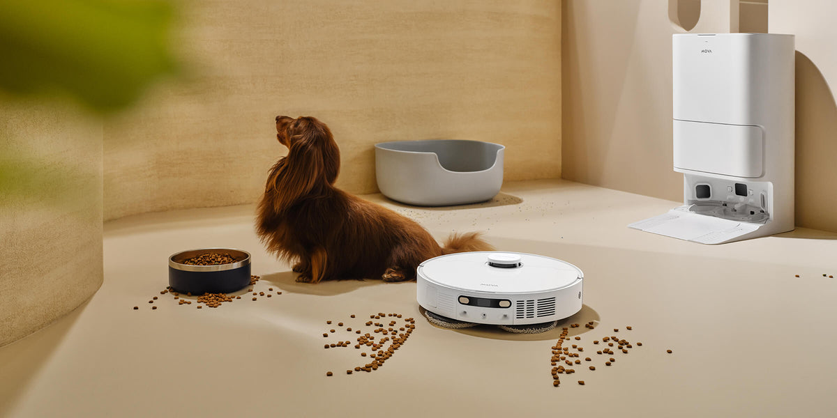 MOVA robot vacuum cleaning spilled kibble beside a long-haired dog, with a self-emptying dock in the background